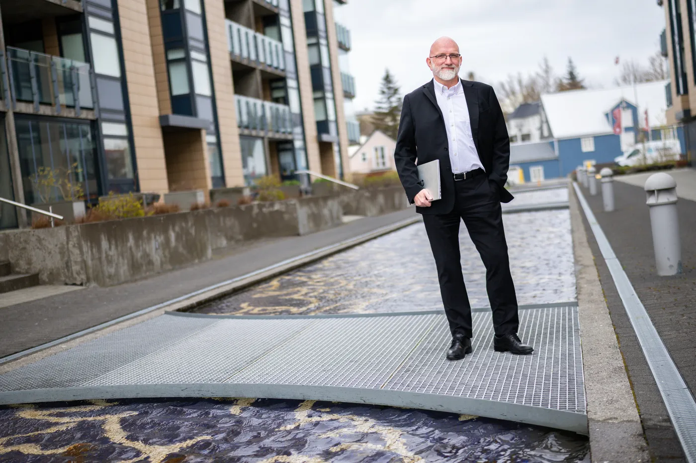 Gísli standing on a footbridge over a stream in town
