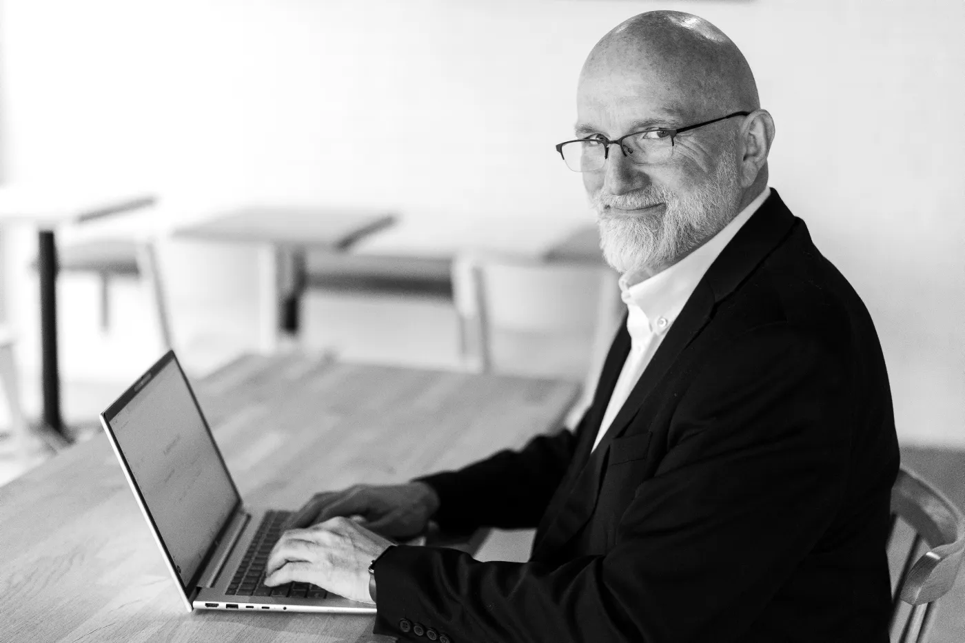 Black and white photo of Gísli at a laptop, looking at the camera